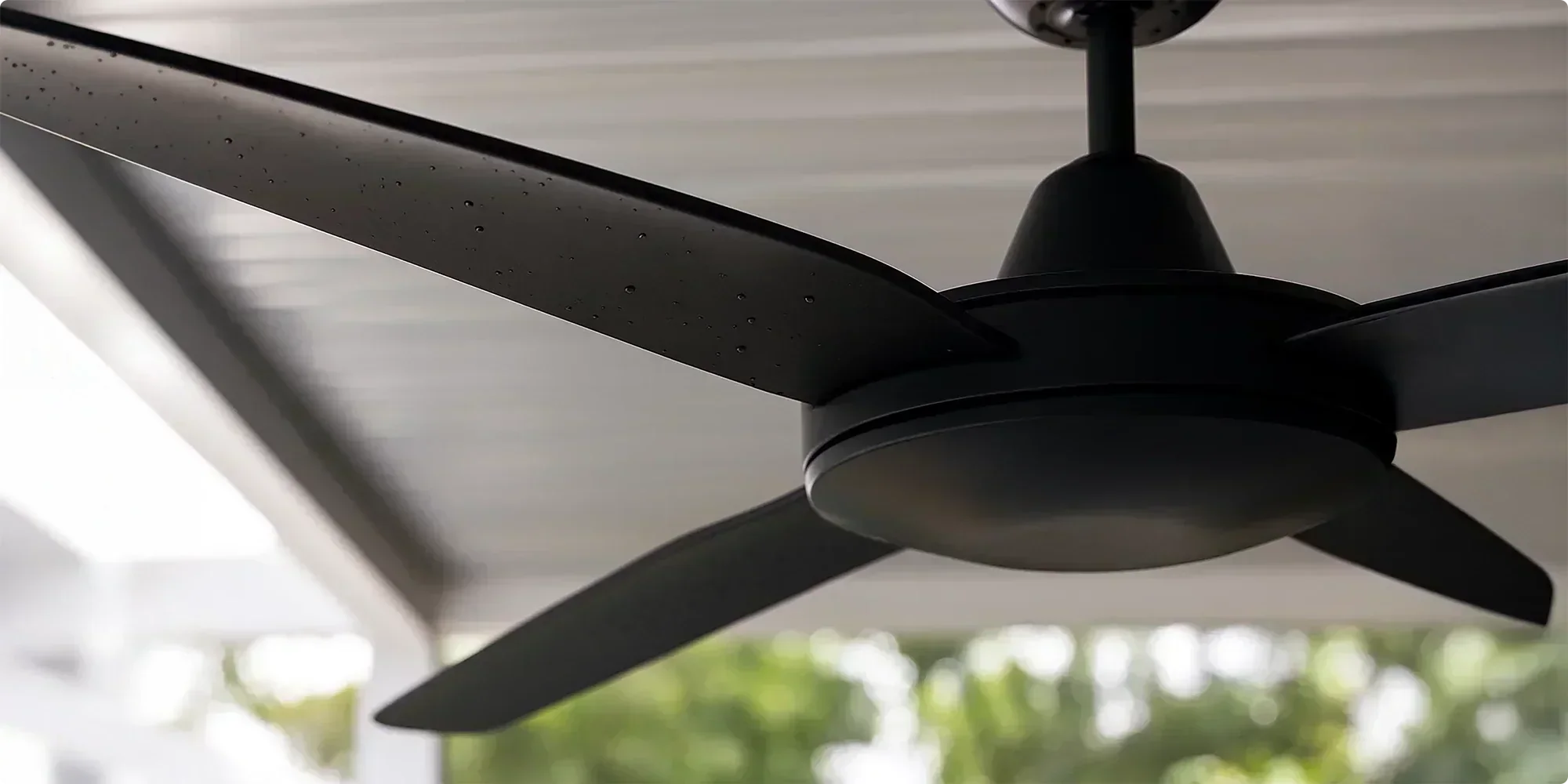 Modern black outdoor ceiling fan with three blades under a covered patio.