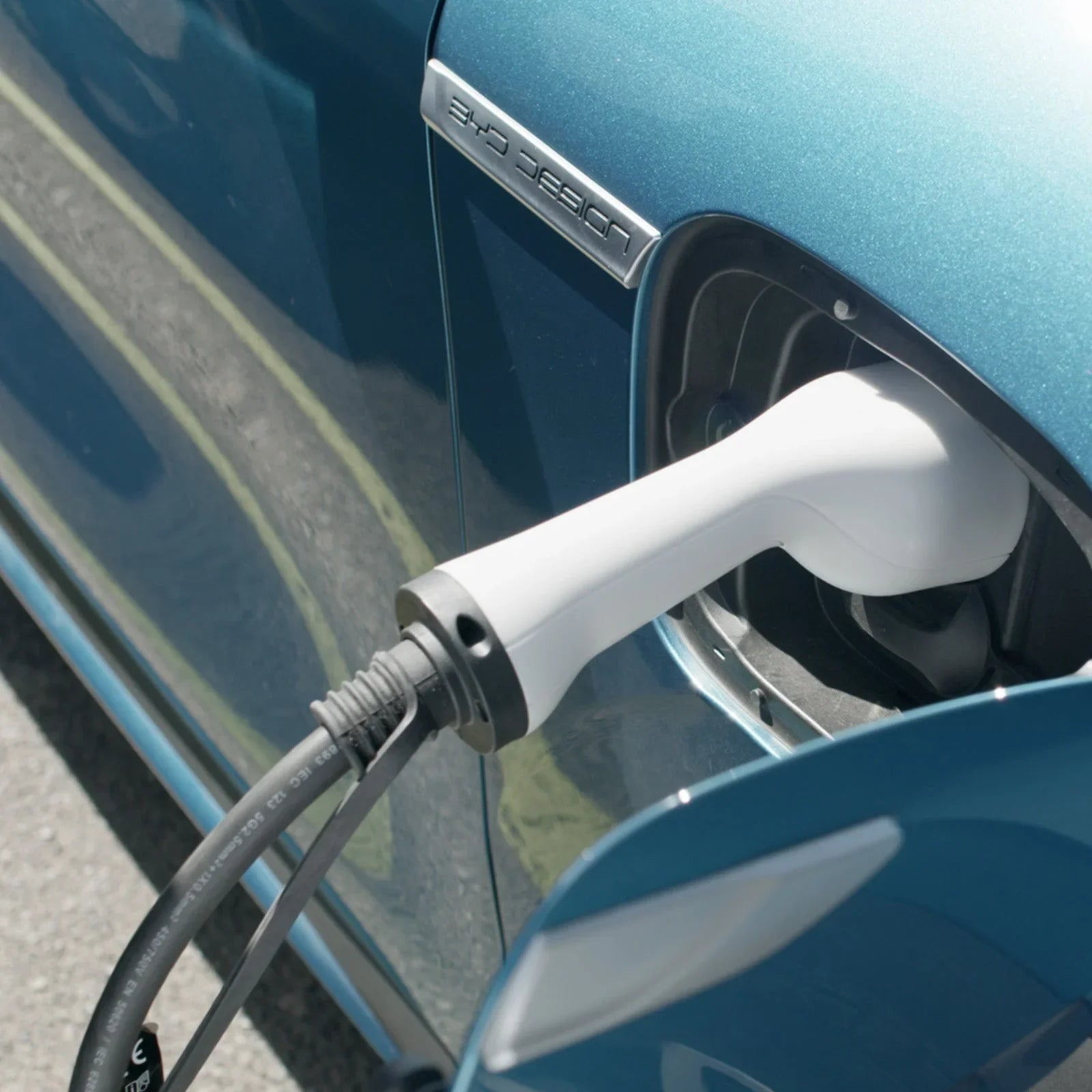 Electric vehicle charging at station, close-up of white charger and blue car